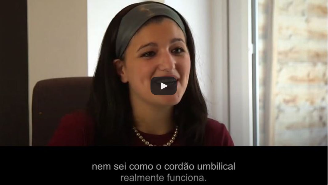 Mulher com colar de pérolas ao lado de uma janela.